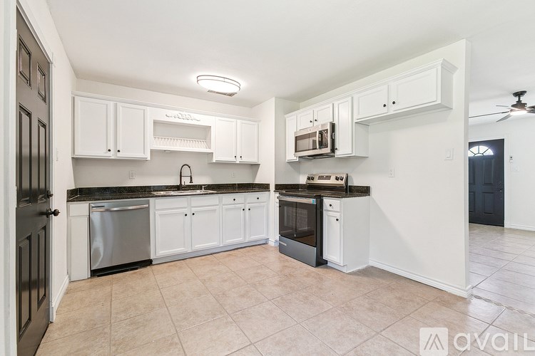 A kitchen with white cabinets and black appliances.
