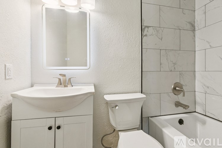 A bathroom with a white sink, toilet, and tub.
