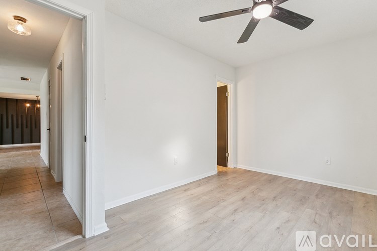 A room with a ceiling fan and wooden flooring.