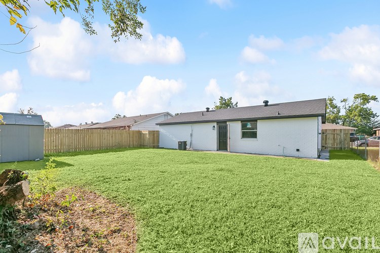 A white house with a grey roof and a green lawn in front.