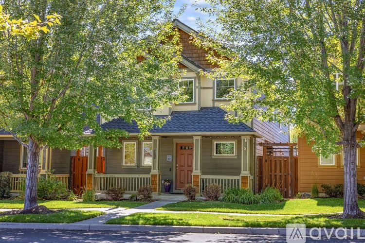 A house with a front porch and a tree in front of it.
