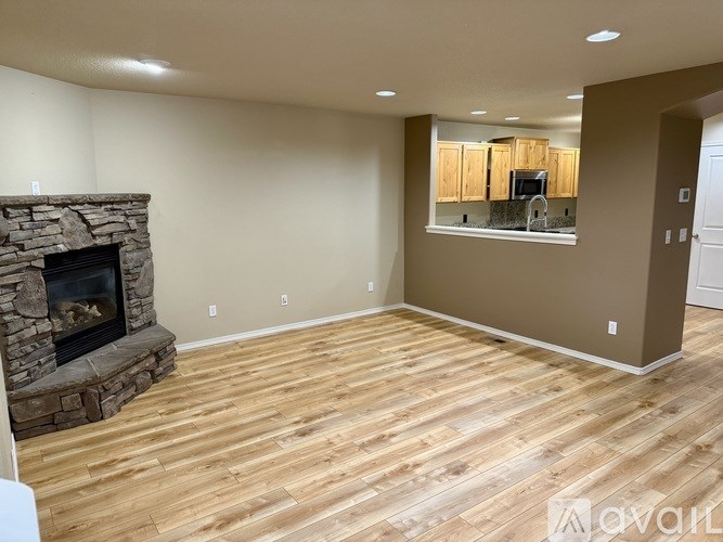 A living room with a stone fireplace and wooden flooring.
