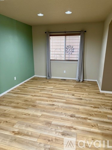 A room with wooden flooring and a window with blinds.