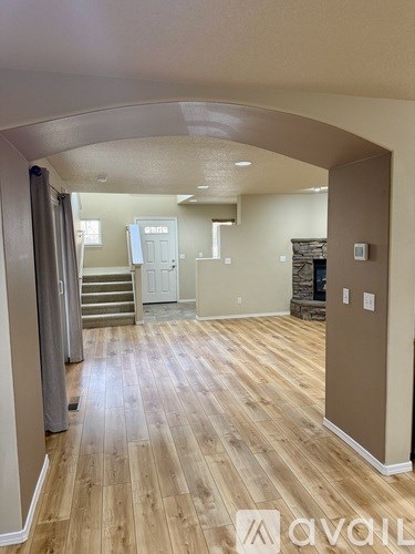 A hallway with wood flooring and a stone fireplace.