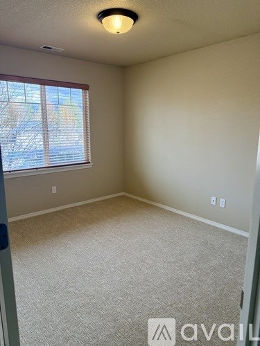 A room with a carpeted floor and a window with blinds.