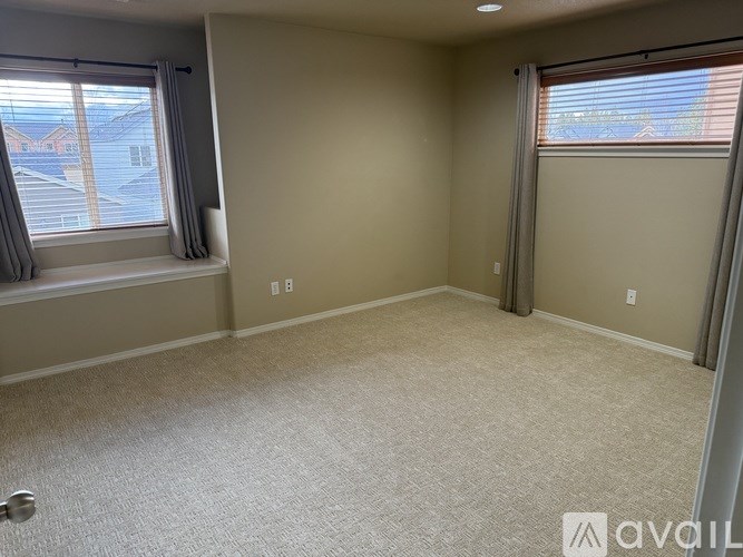 A room with a carpeted floor and two windows.
