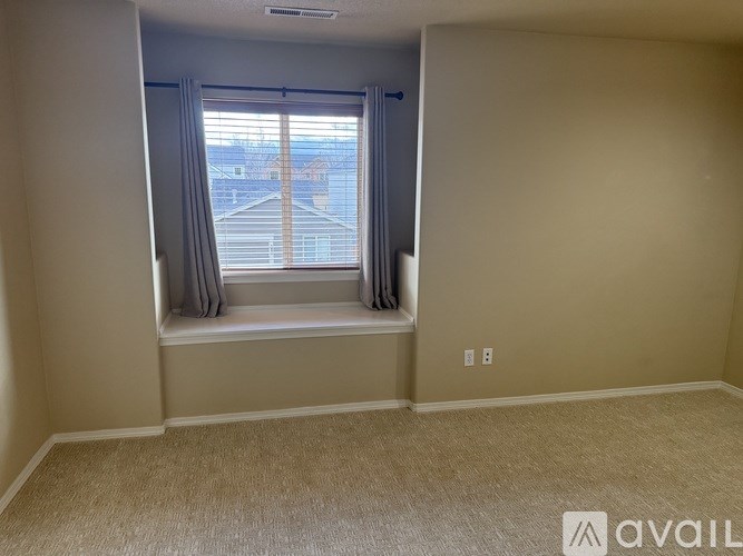 A room with a window and a carpeted floor.