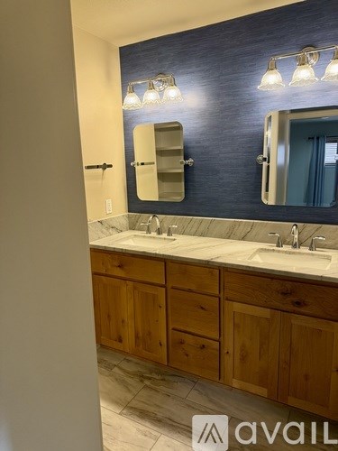 A bathroom with a sink, mirror, and wooden cabinets.