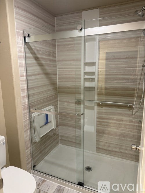 A modern bathroom with a glass shower door and a toilet.