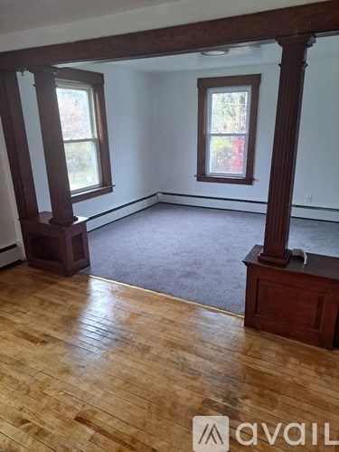 A room with wooden floors and two windows.
