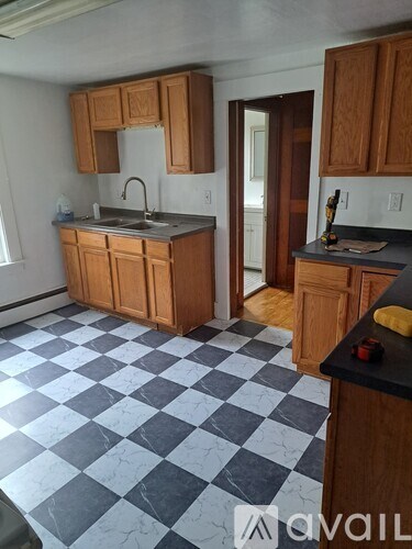A kitchen with wooden cabinets and a checkered floor.