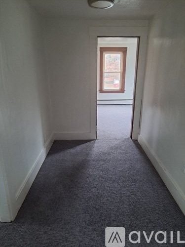 A carpeted hallway with a door at the end.