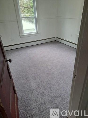 A room with a carpeted floor and a window.