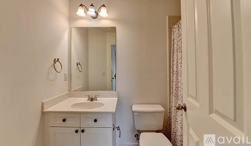 A bathroom with a sink, toilet, and mirror.