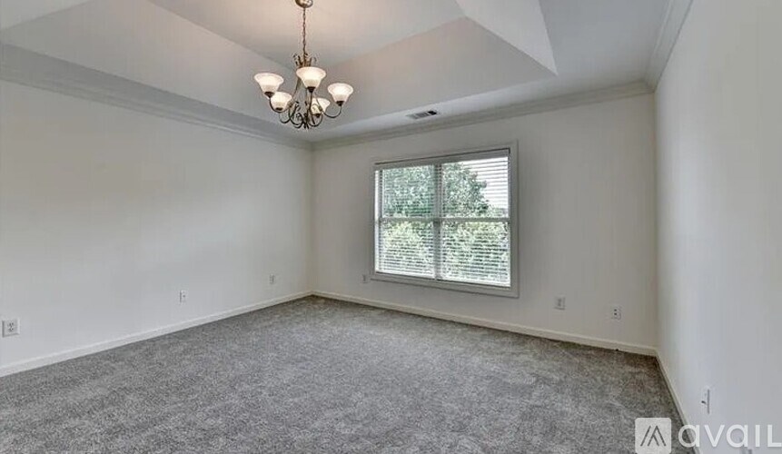 A room with a grey carpet and a chandelier.