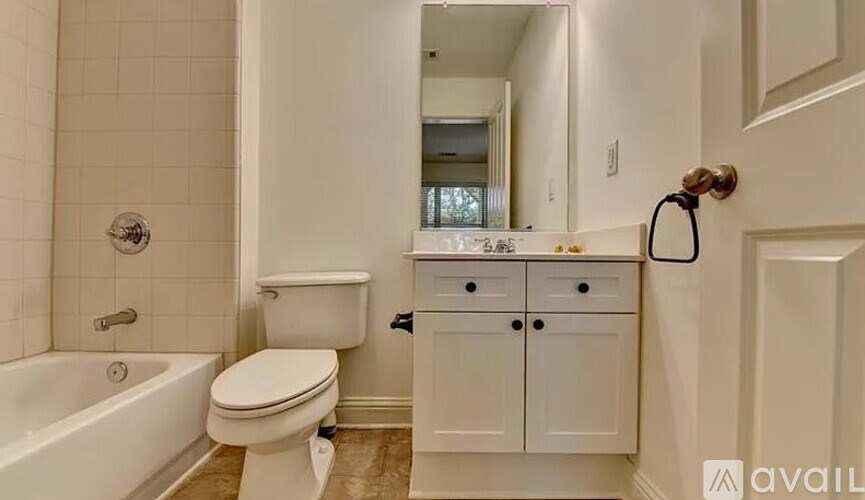A bathroom with a white toilet, a white bathtub, and a white cabinet.