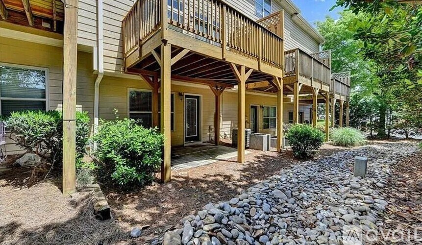A row of houses with balconies and a gravel pathway in front.