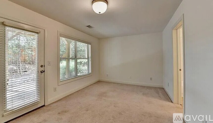 A room with a carpeted floor and a window with blinds.