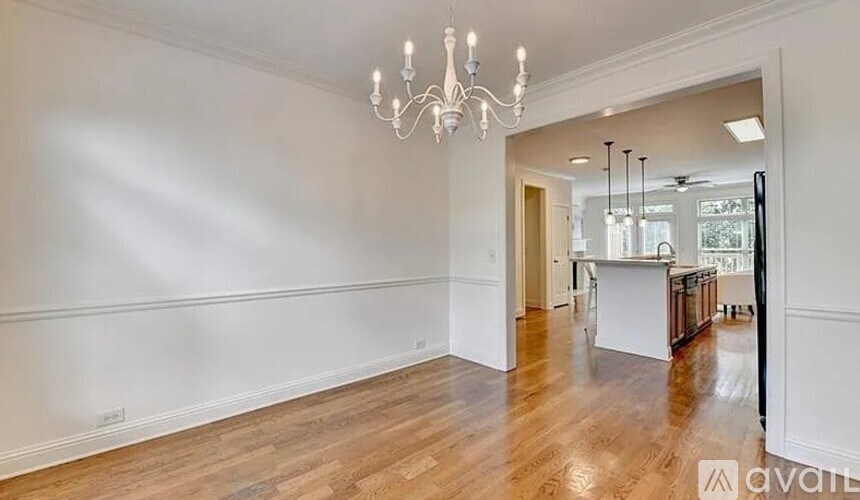 A large, empty room with wooden floors and a chandelier.