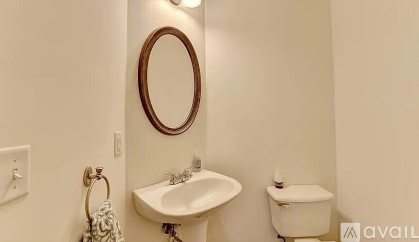 A bathroom with a toilet, sink, and mirror.