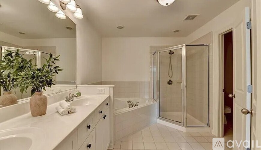 A bathroom with a white countertop and a glass shower stall.
