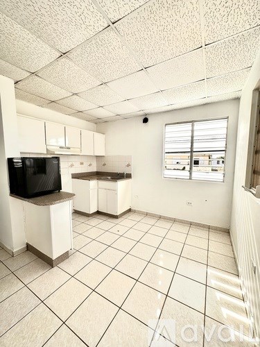 A spacious kitchen with white cabinets and a black fridge.