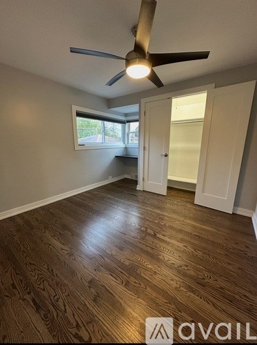 A room with a ceiling fan and wooden flooring.