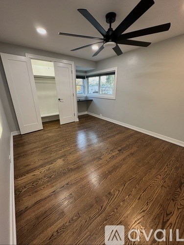 A room with a ceiling fan and wooden flooring.