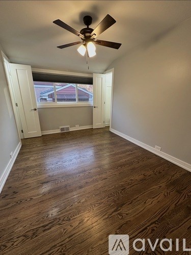A room with a ceiling fan and wooden flooring.