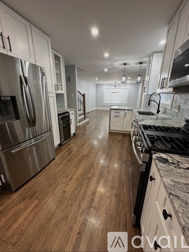 A modern kitchen with stainless steel appliances and wooden flooring.