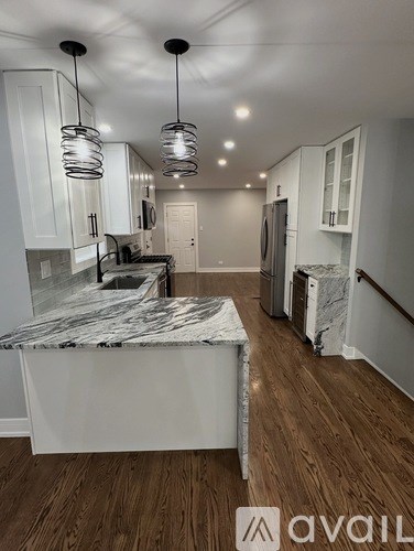 A kitchen with a marble island and wooden floors.