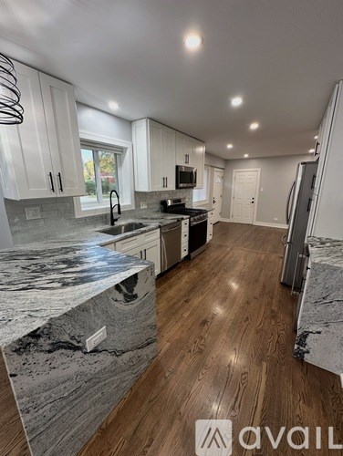 A kitchen with a marble countertop and wooden flooring.