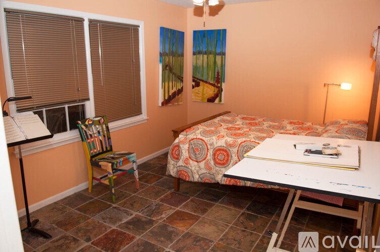 A room with a bed, a chair, and a painting on the wall.