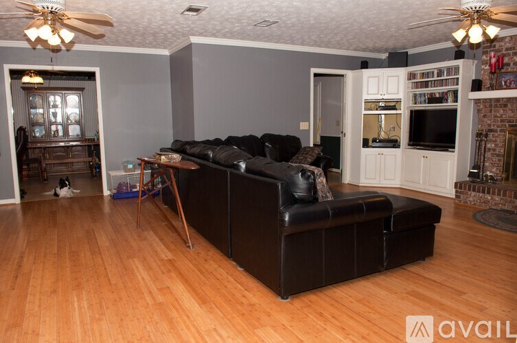 A living room with a black couch and wooden floors.