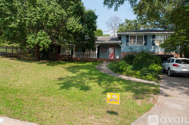 A yellow sign with black text is in the foreground of a grassy area.