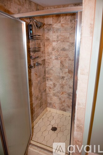 A shower area with a tile floor and tiled walls.