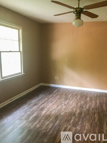 A room with a ceiling fan and wooden flooring.
