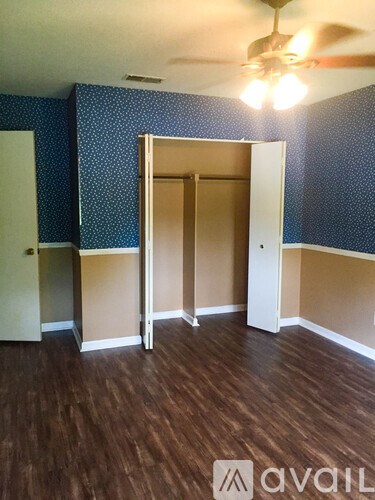 A room with a ceiling fan and a wooden floor.