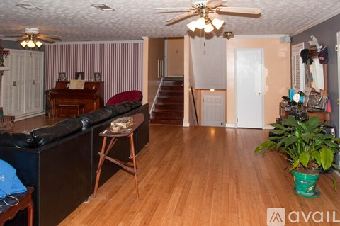A living room with a black couch and a wooden floor.