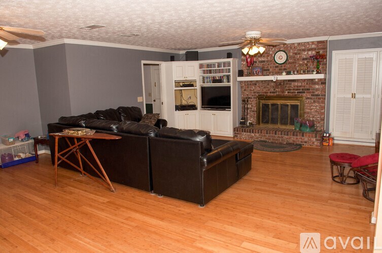 A living room with a black couch and a wooden floor.