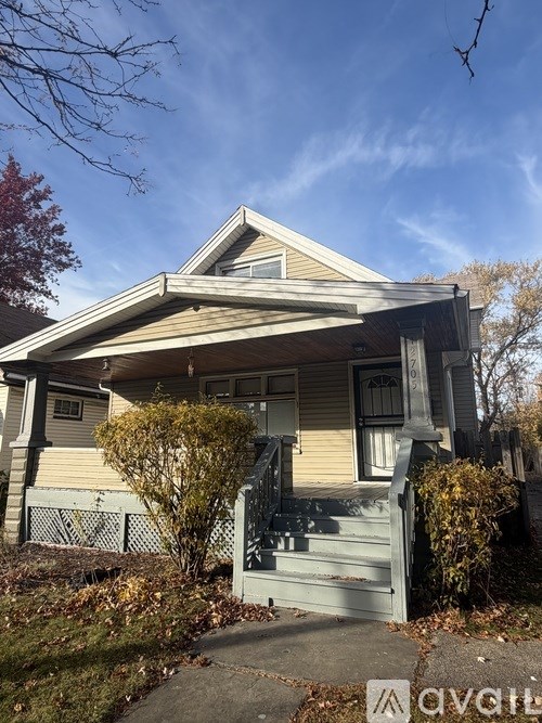 A house with a porch and a tree in front.