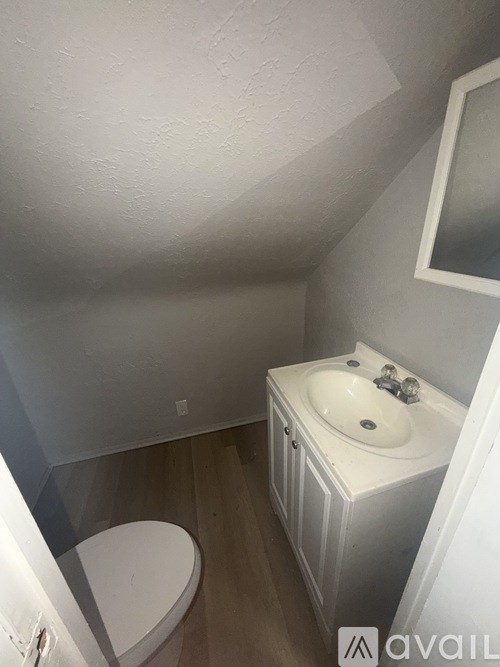 A bathroom with a toilet, sink, and mirror.
