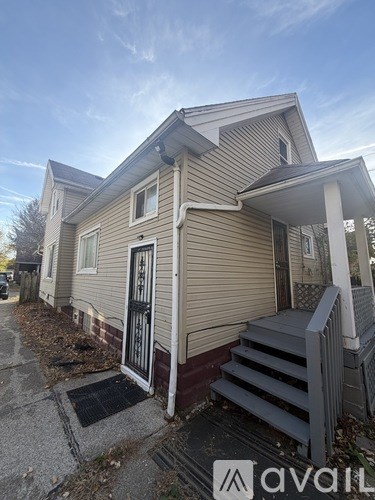 A beige house with a black door and a small porch.