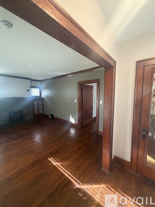 A room with wooden floors and a doorway leading to another room.