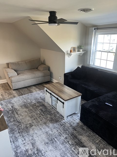 A living room with a black couch and a grey rug.