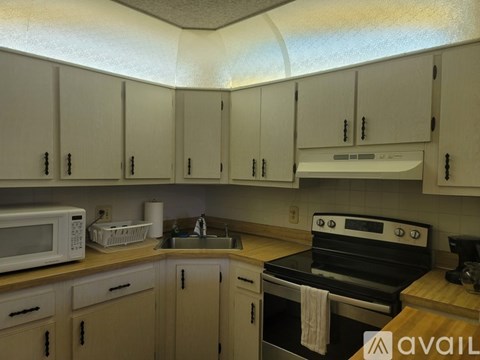 A kitchen with a white microwave, white oven, and wooden countertops.