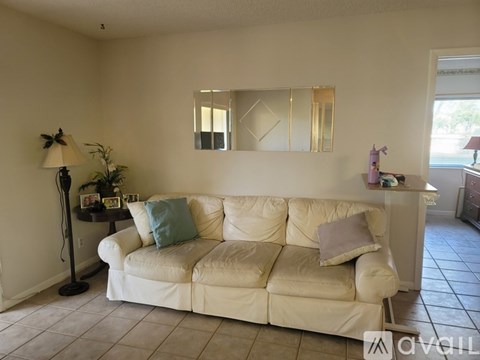 A white couch with a blue pillow is in the middle of a room.