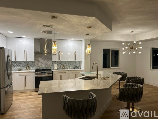 A modern kitchen with a marble island and pendant lights.