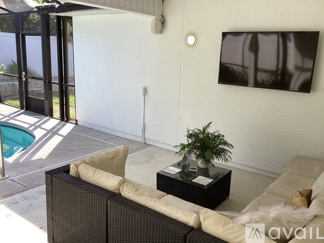 A living room with a couch, a coffee table, and a pool outside the window.