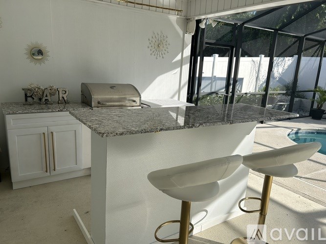 A bar area with a marble counter and two white bar stools.